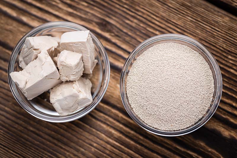 bowl of fresh yeast and a bowl of active dry yeast on a wooden board