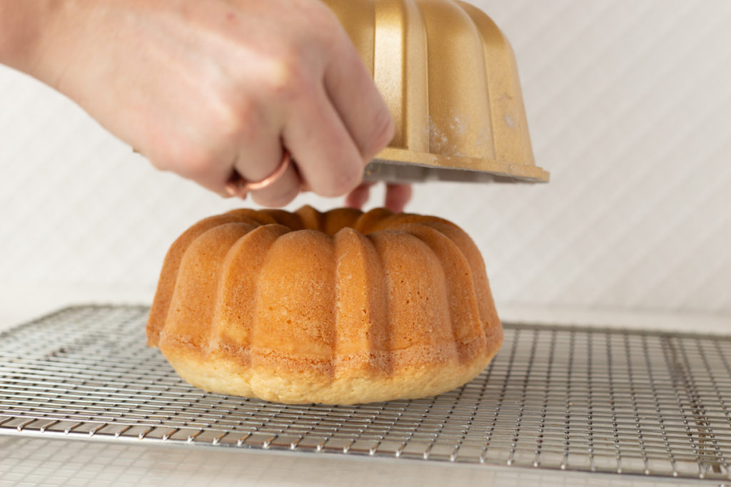 the cake pan is being lifted off of the baked cake