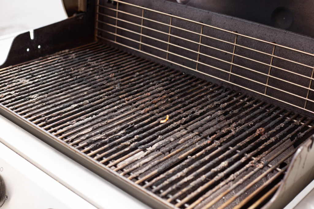 The stainless steel grill grates are dirty and covered in burnt food. 