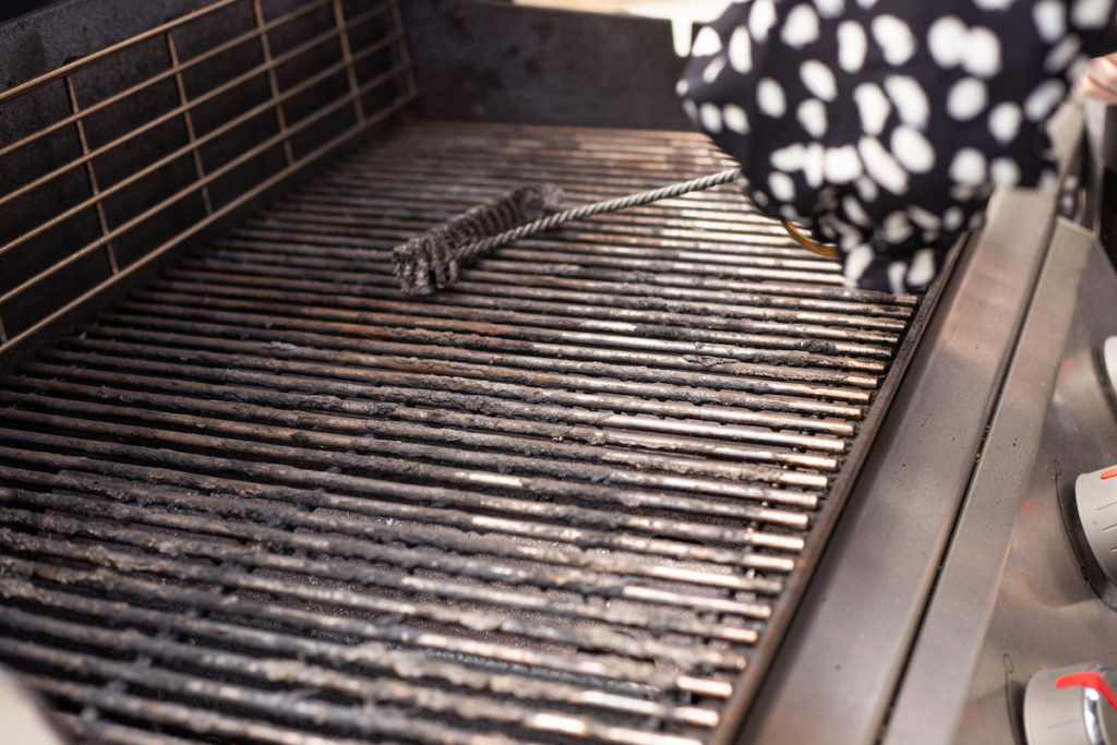 Grill brush is scrubbing the gas grill grates