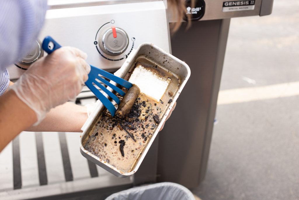 The gas grill drip tray being cleaned.