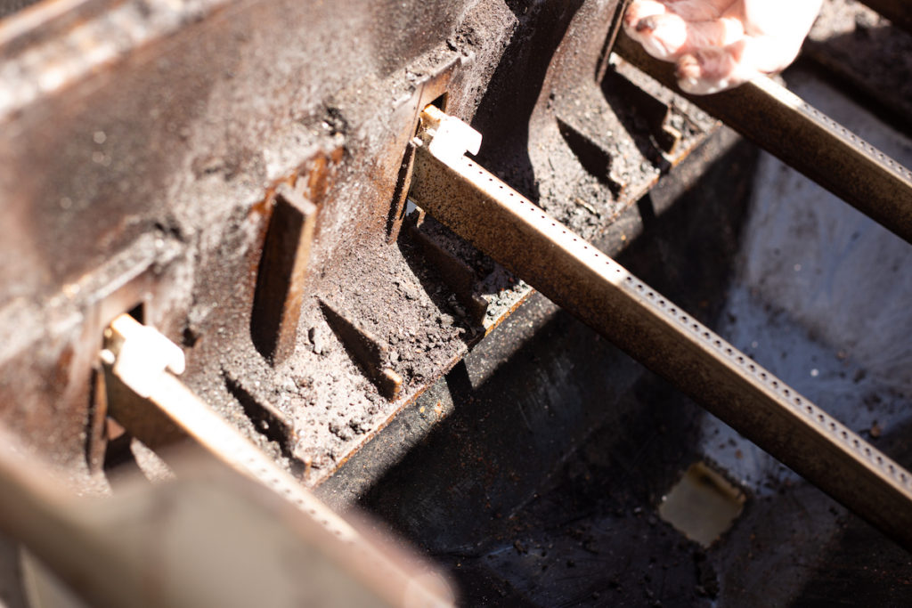 The gas grill cook box is exposed and dirty.