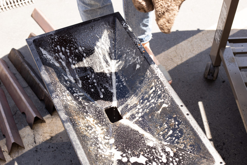 The grill cook box is sprayed with cleaner. 