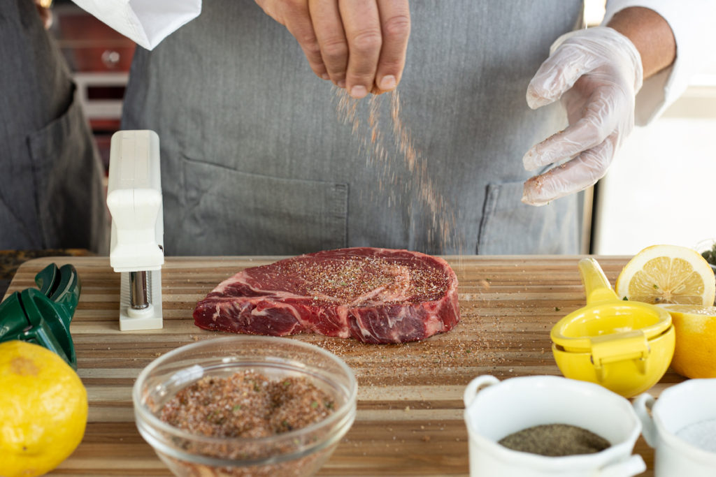 Sprinkling Sweet BBQ Rub onto a ribeye steak. 