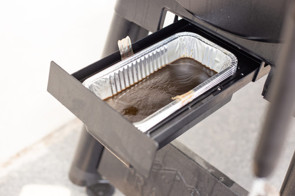The grease tray is filled and is about to be removed.