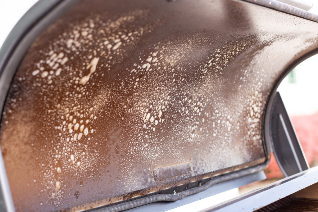 Pellet grill lid is sprayed with cleaner