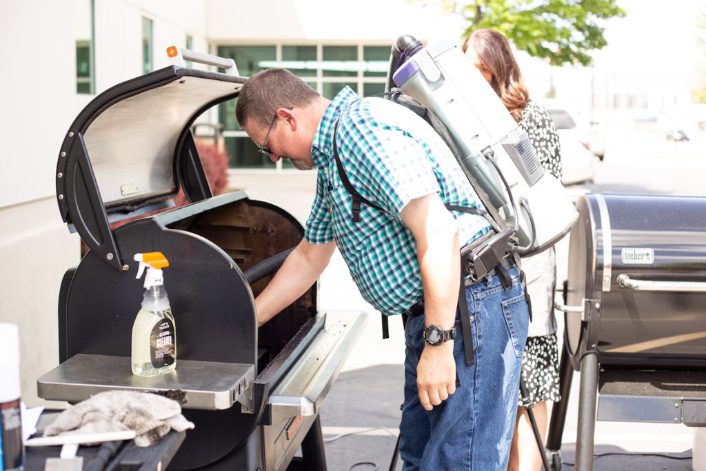 Burton is vacuuming the pellet grill interior. 