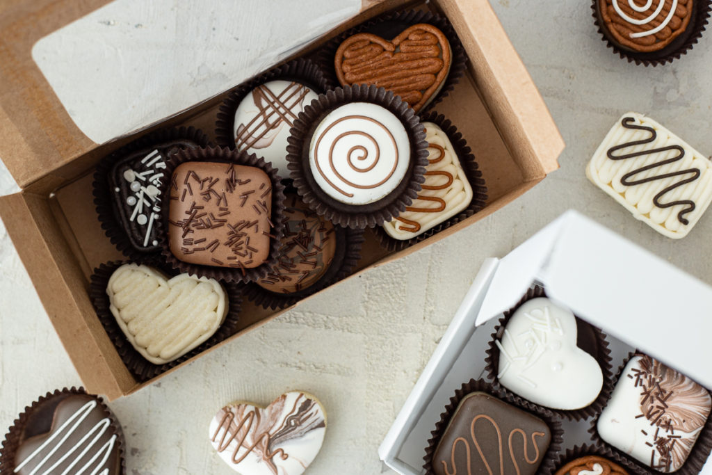 Decorated chocolate sugar cookies are arranged into candy boxes, ready for delivery. 