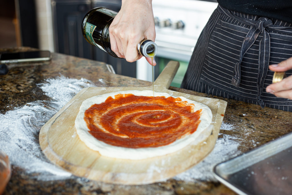 Drizzling olive oil onto the neapolitan pizza