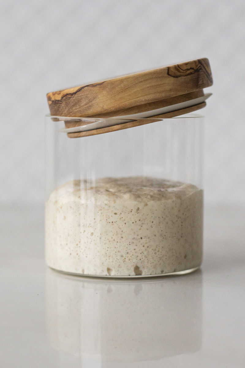 sourdough starter in a glass jar with loose fitting lid