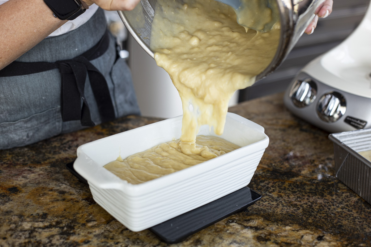 Pouring the banana bread batter into a ceramic bread pan