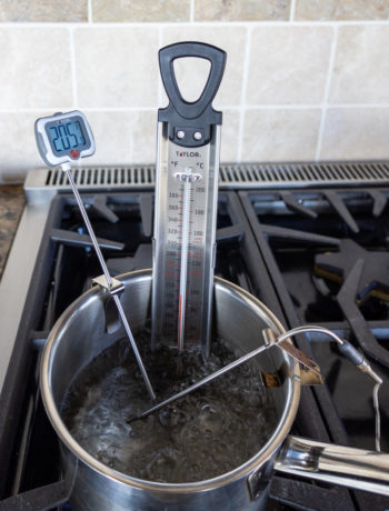 Three thermometers measuring the temperature of a pot of boiling water