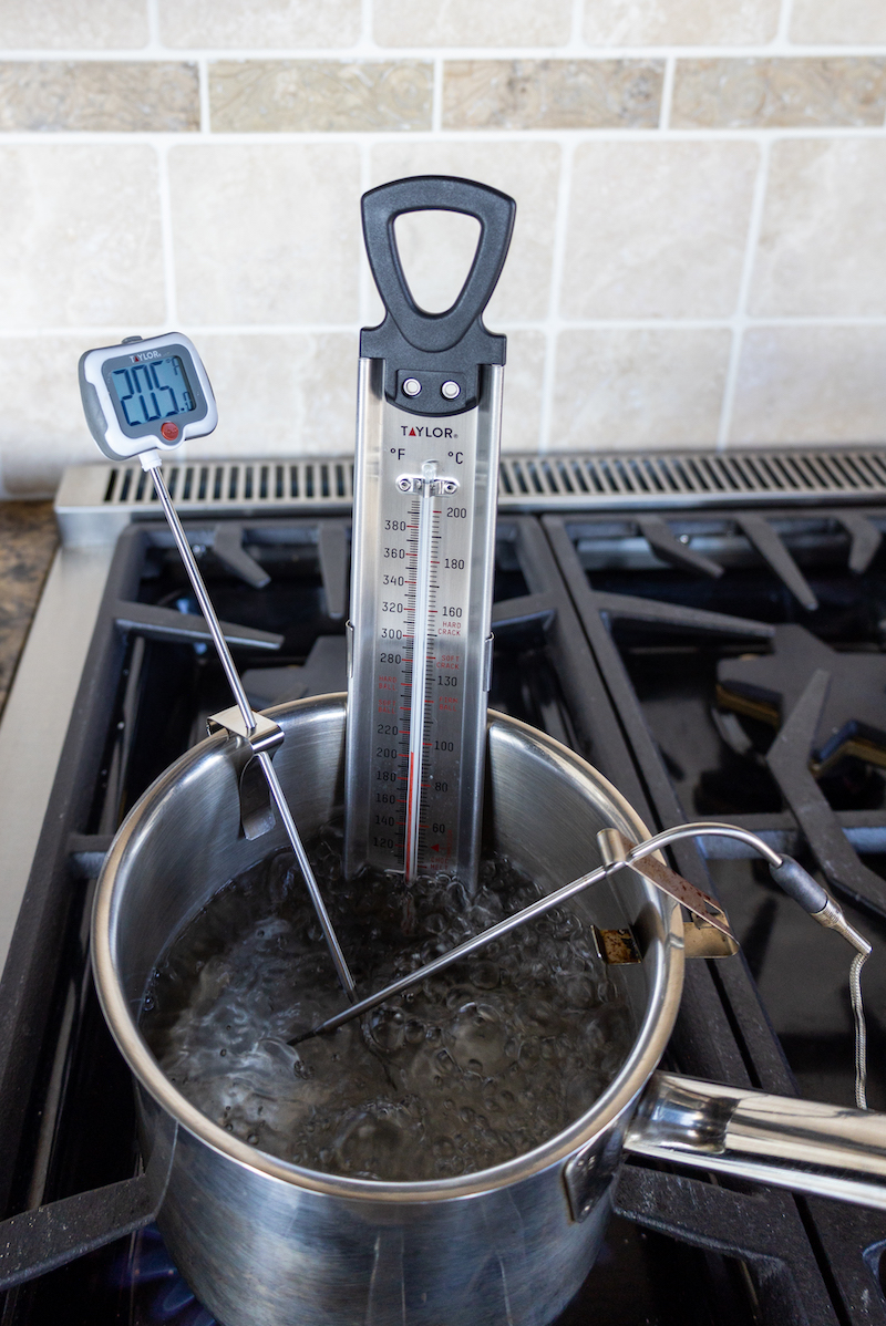 Three thermometers measuring the temperature of a pot of boiling water