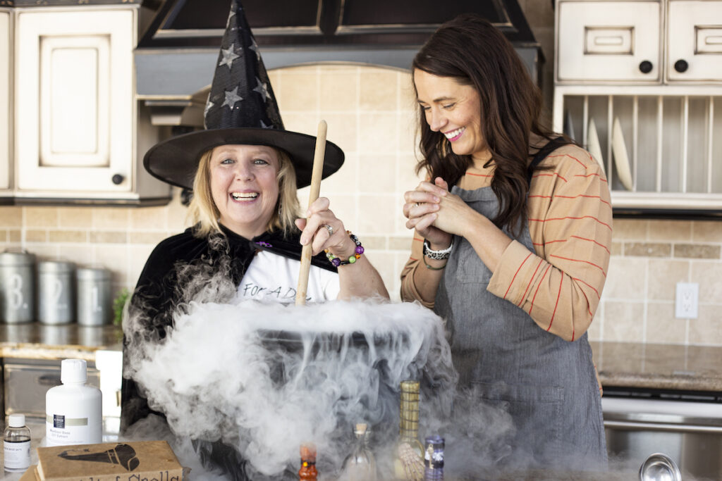 Heather and Marcie making homemade root beer in a witches cauldron