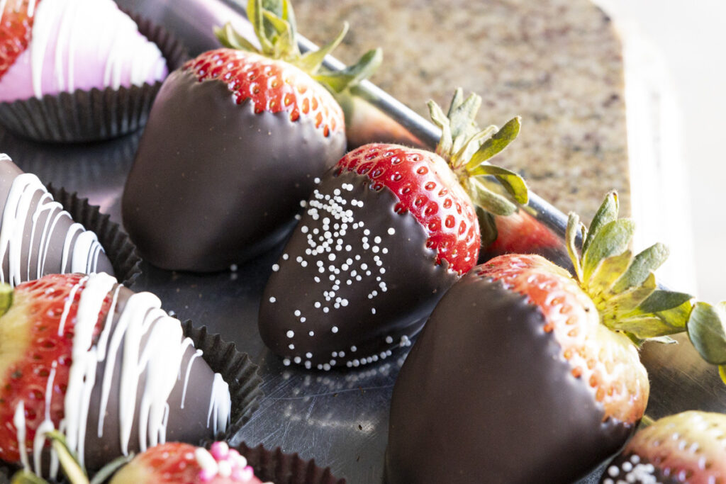 row of chocolate-dipped strawberries with drizzles and sprinkles